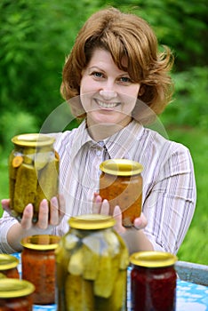 Housewife with homemade pickles and jams in garden