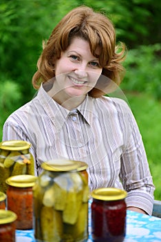 Housewife with homemade pickles and jams in garden