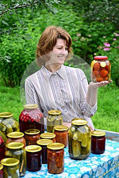 Housewife with homemade pickles and jams in garden