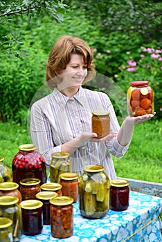 Housewife with homemade pickles and jams in garden