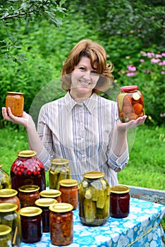 Housewife with homemade pickles and jams in garden