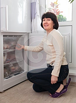 Housewife at kitchen near freezer