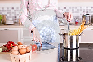 Housewife on kitchen with pasta, eggs and vegetables