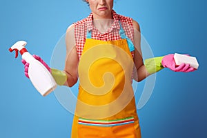 Housewife with kitchen sponge and bottle of detergent on blue