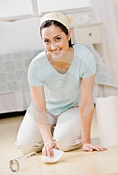 Housewife kneeling in bedroom wiping up spill