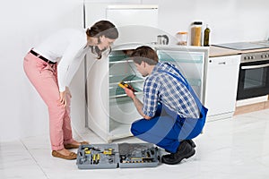 Housewife Looking At Worker Repairing Refrigerator