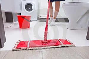 Housewife mopping the floor in a bathroom