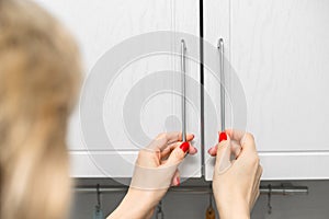 housewife opens kitchen cabinet doors with both hands, close-up.