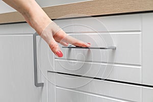 housewife opens a kitchen cabinet drawer with her hand, close-up