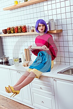 housewife with purple hair sitting on kitchen counter with