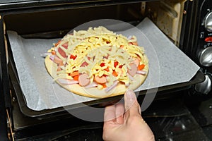 Housewife putting homemade fresh uncook pizza to an oven