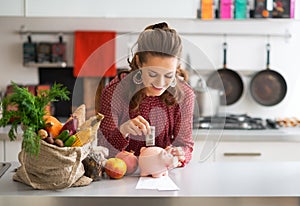 Housewife putting money into piggy bank