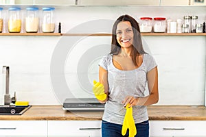 Housewife putting on yellow gloves to wash dishes in kitchen.