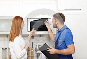 Housewife and repairman near microwave oven