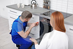 Housewife with repairman near modern oven