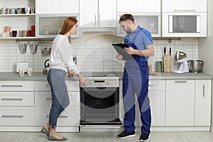 Housewife with repairman near modern oven