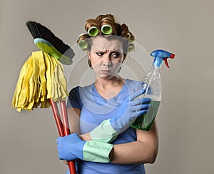 housewife in rubber gloves and hair rollers holding cleaning spray bottle broom and mop frustrated