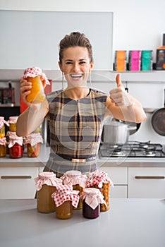 Housewife showing jars with homemade fruits jam