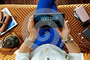 Housewife sitting on divan in modern living room videogaming