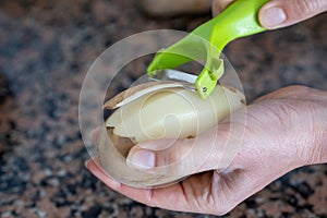 Housewife slicing potato in the kitchen with special slicer