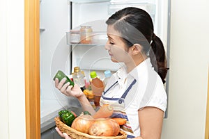 Housewife standing at the open refrigerator