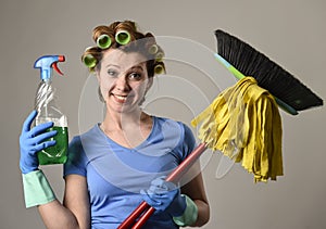 Housewife stereotype hair rollers and washing gloves holding mop broom and detergent spray bottle