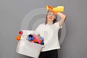 Housewife takes care of clothing. Domestic appliances aid in housework. Tired exhaused woman wearing whote t-shirt with laundry