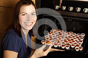 Housewife taking cupcakes from oven