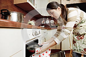 Housewife taking frying pan from oven