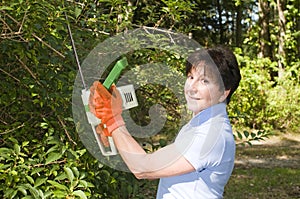 Housewife trimming bushes hedge trimmer