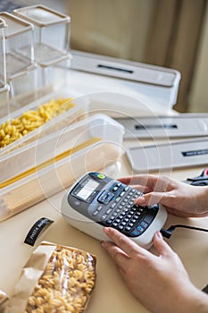 Housewife typing names of pasta kinds use label machine device food product storage organization