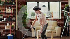 Housewife using vacuum cleaner to tidy up living room