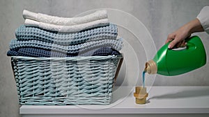 The housewife washes clothes. A young woman pours liquid washing powder.