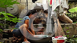 Housewife washing clothes in untidy backyard