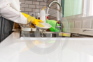 Housewife wearing yellow rubber gloves washing dishes