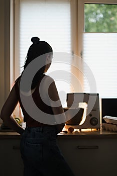 Housewife woman baking at home using kitchen planetary mixer in a cozy kitchen