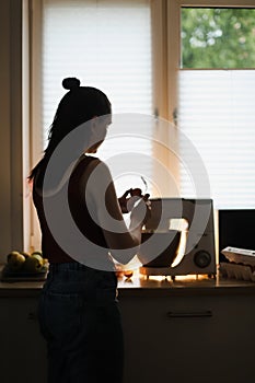 Housewife woman baking at home using kitchen planetary mixer in a cozy kitchen