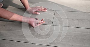 Housewife woman points finger at dirt stain on laminate floor closeup