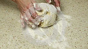 Housewives are kneading and crumpling dough on a bright kitchen table sprinkled with white wheat flour. Close-up of