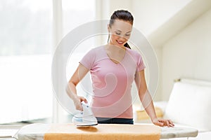 Woman or housewife ironing towel by iron at home