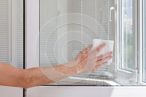 Houseworker clean plastic pvc window with napkin.