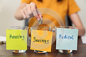 Housing, medical with saving notepaper pasted on the bottle with coins inside, young woman uses a calculator.