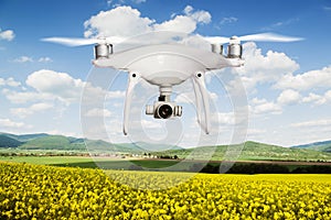 Hovering drone taking pictures of canola field and green hills