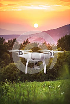 Hovering drone taking pictures of green nature at sunset