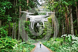 Hovering drone taking pictures of man running in forest.