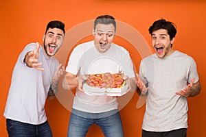 How delicious! Joyful mates with pizza looking at camera