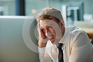How did I let this happen. a bored businessman staring blankly at his computer screen.