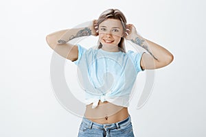 How do you like my new outfit. Portrait of happy charming european female student with tattoos in cropped top and jeans