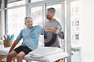 How does that feel. a young male physiotherapist assisting a senior patient in recovery.