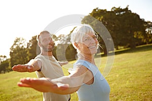 This is how we keep ourselves feeling young. Portrait of a happy mature couple doing yoga together outdoors.